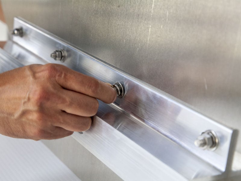 Person using screws and bolts to mount a bar to a sign